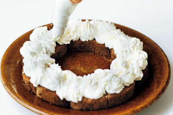 潰したロールケーキにホイップを絞る様子