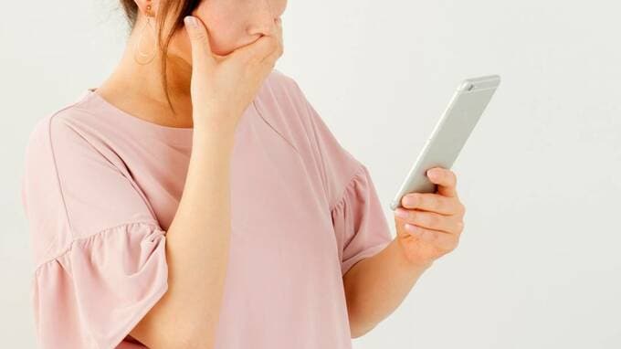 スマホを見て口をおさえる女性