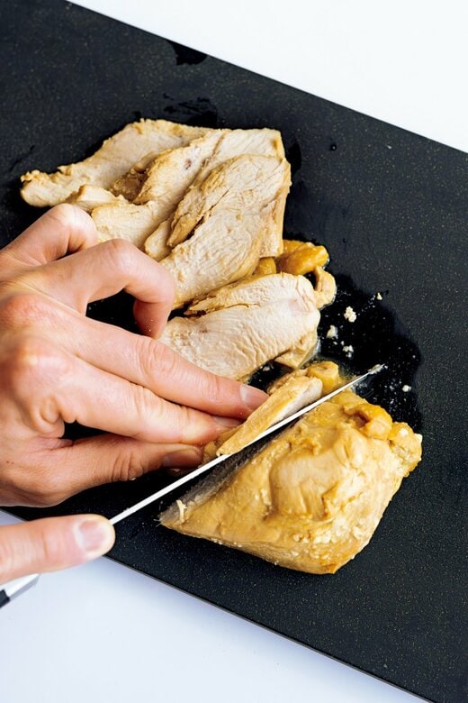 包丁で鶏胸肉をスライスする様子