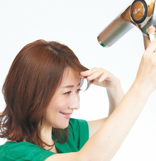 前髪の根元にドライヤーを当てる女性