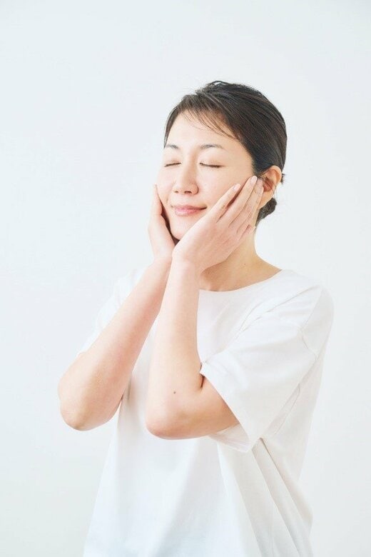 目をつむり、両手を両頬にあてる女性