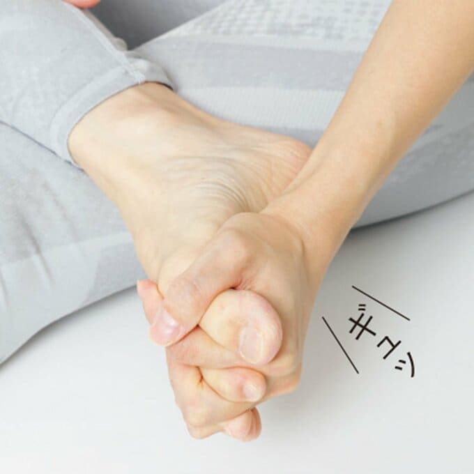 足指の間に手指を入れて、ギュッと握っている
