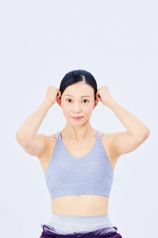 こめかみにこぶしを当てる女性