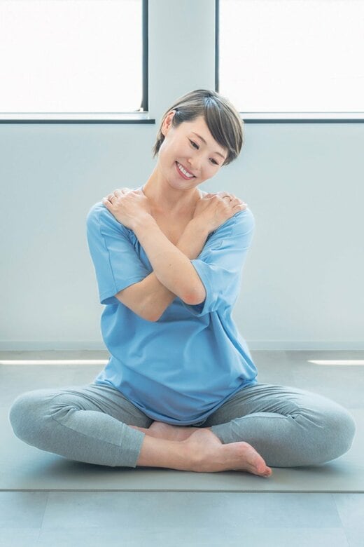 体の前で両腕をクロスして首を回すヨガのポーズ