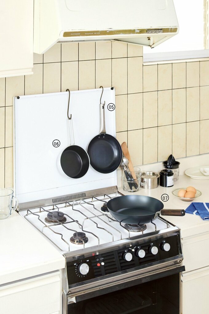 コンロとその前の壁に並ぶフライパンや鍋