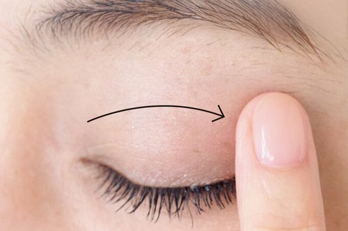 閉じたまぶたの上を指先で押さえる女性