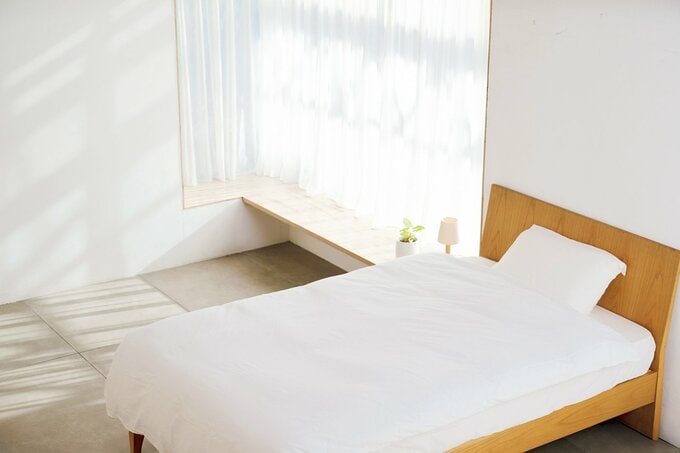 白が基調の部屋に無印良品の寝具がベッドに敷かれた様子