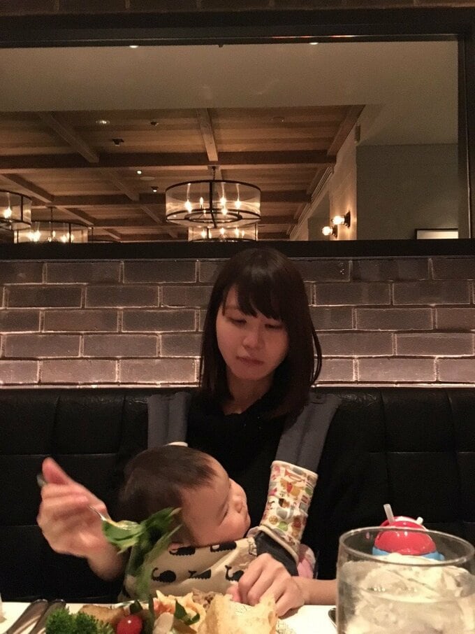 赤ちゃんを抱いて食事をする女性