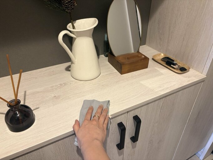白い玄関収納を布巾でふいている手元