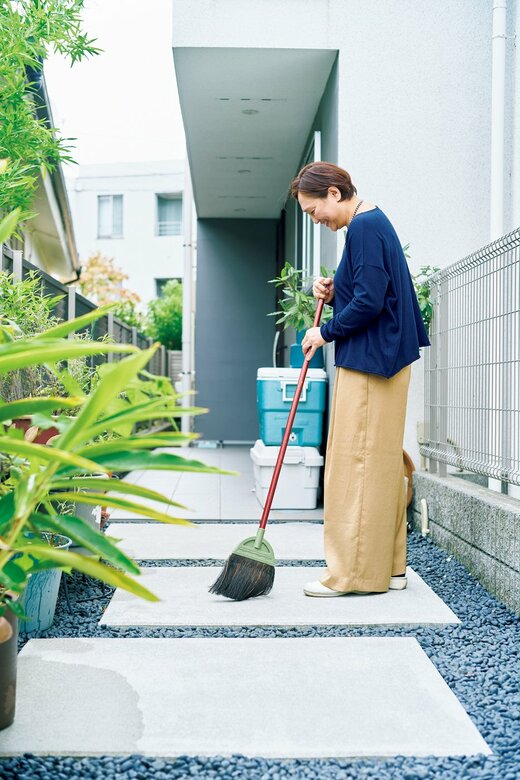 玄関ポーチをほうきで掃く五味さん