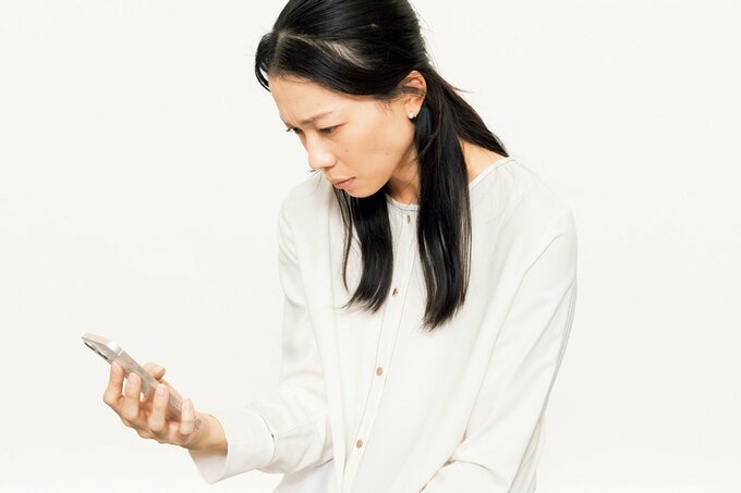 猫背になってスマホを見る女性