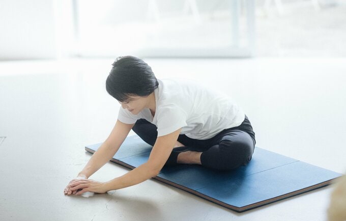 股関節を開いて前屈をする藤井恵さん