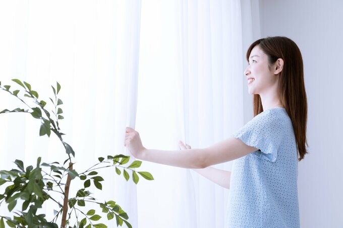 カーテンを開ける女性
