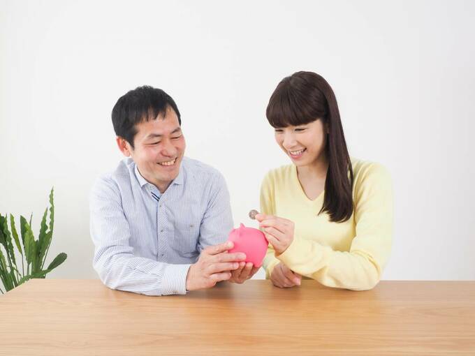 豚の貯金箱を持つ男女