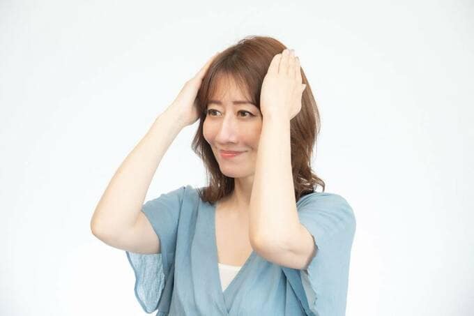 両手で髪をおさえる