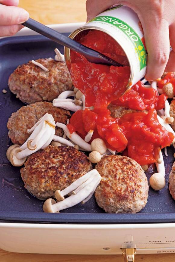 ハンバーグにトマトソースをかける様子