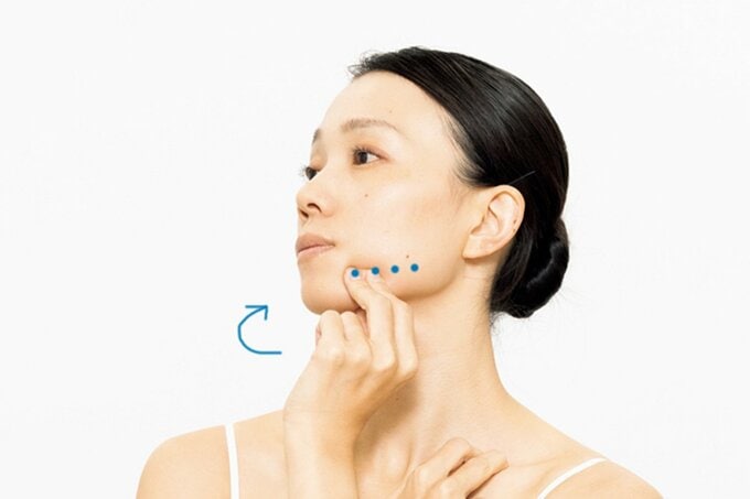 フェイスラインを指でつまみ、首を左右に振る女性