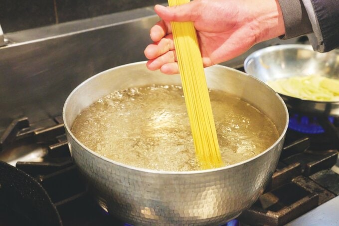 沸騰した鍋にパスタを入れる様子