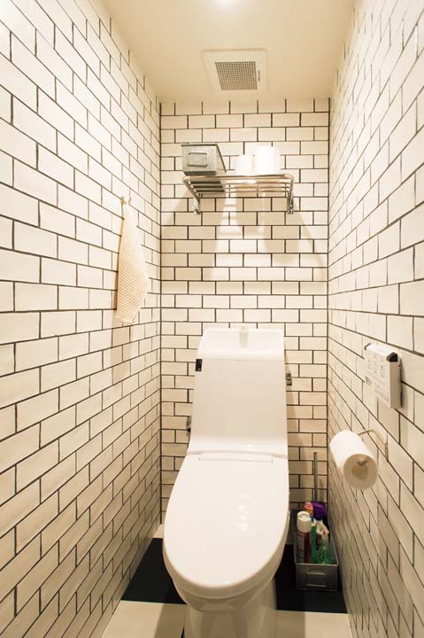 壁を馬目地貼りのタイルで仕上げたトイレ