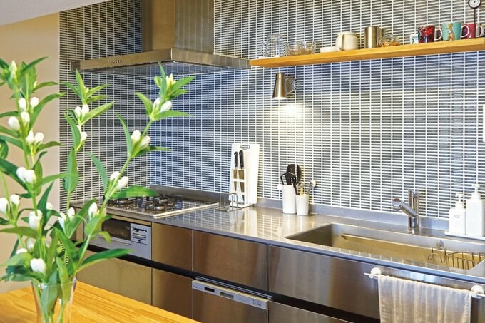 ステンレス製のキッチンに合わせて、ブルーグレーのアクセントタイルを壁面に採用