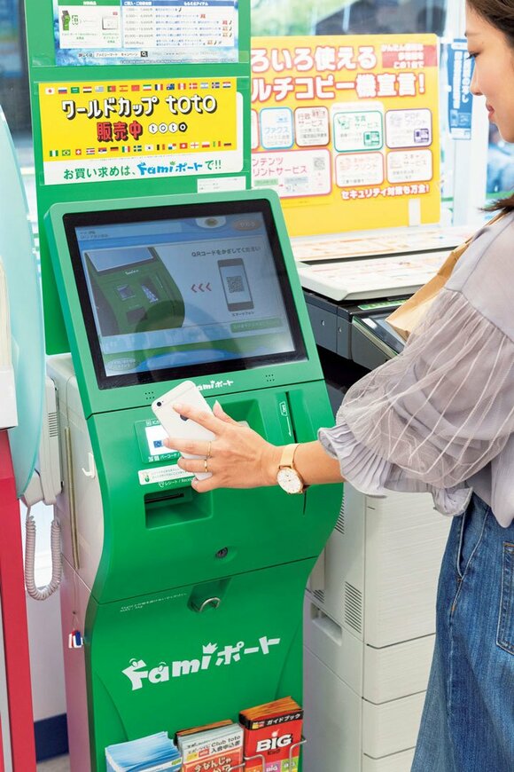 コンビニの端末にQRコードをかざしている様子