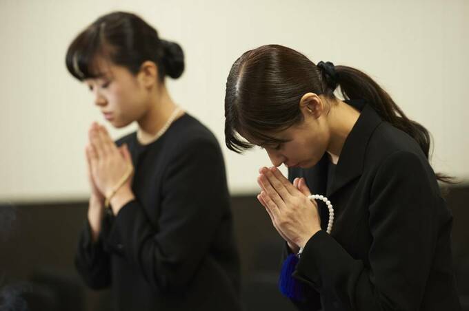 手を合わせる女性2人