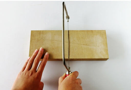 糸ノコを使い、鉛筆で引いたラインに沿ってトレイを半分にカット