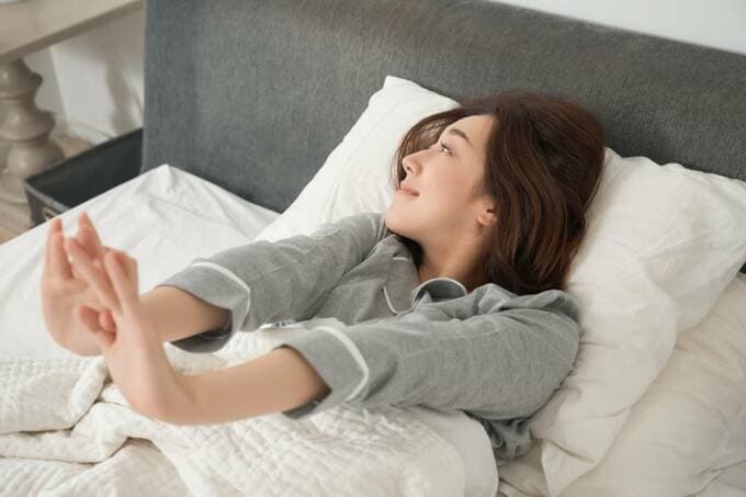ベッドで伸びる女性