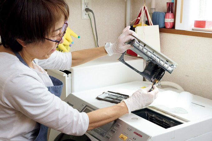 洗濯機を掃除するハウスキーパー