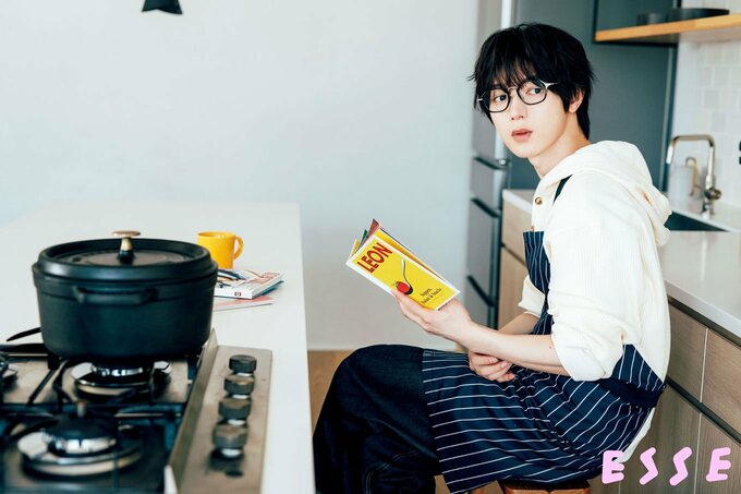鍋の中のサラダチキンが出来上がるのを待ちながらレシピ本を読む七五三掛龍也さん 