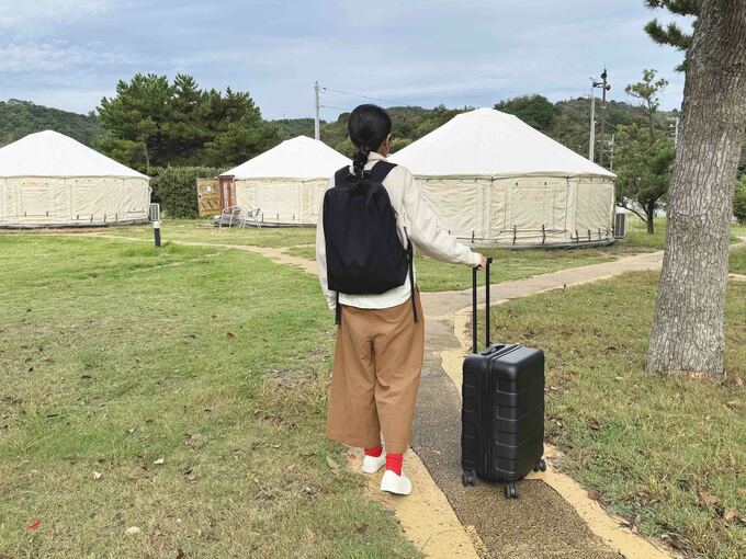 キャリーケースをもつ村上はなさんの後ろ姿