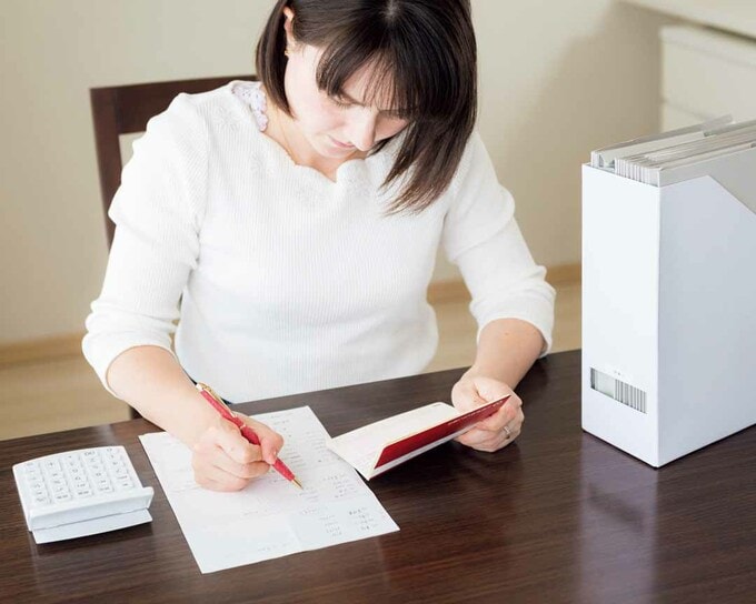 書類を整理し固定費をチェックする様子