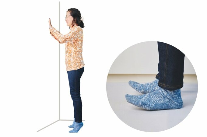 かかと落とし体操をする草野かおるさんとその足元