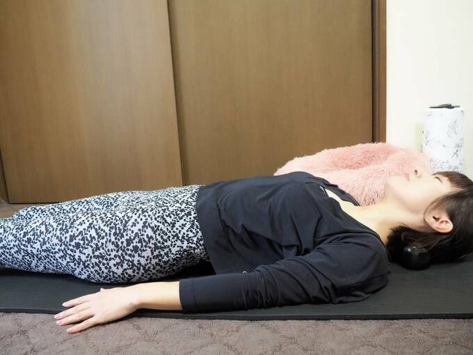 首にツボ押しを置いて寝る女性