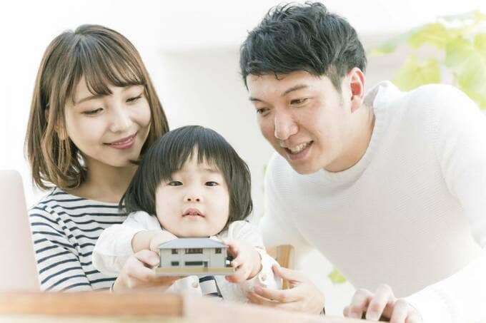 家の模型を持つ子どもと夫婦