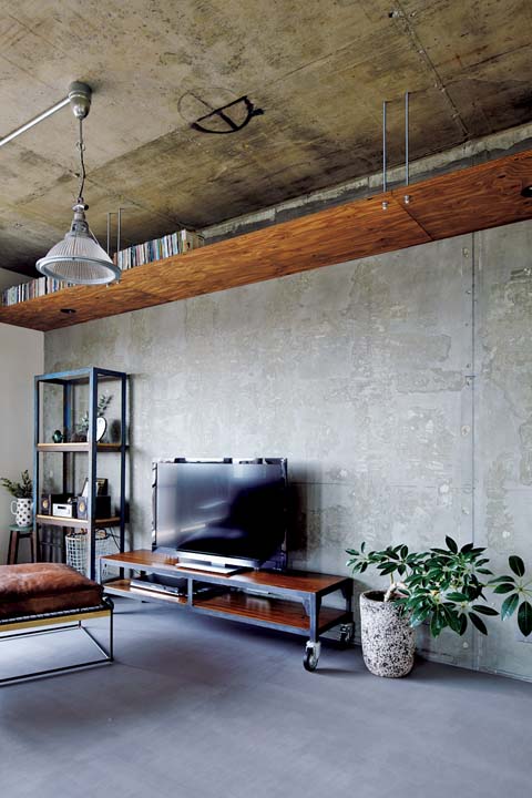 上部に棚を設置したモルタル壁のリビング