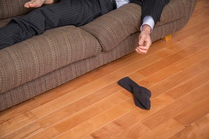 ソファで寝る人と床に落ちた靴下