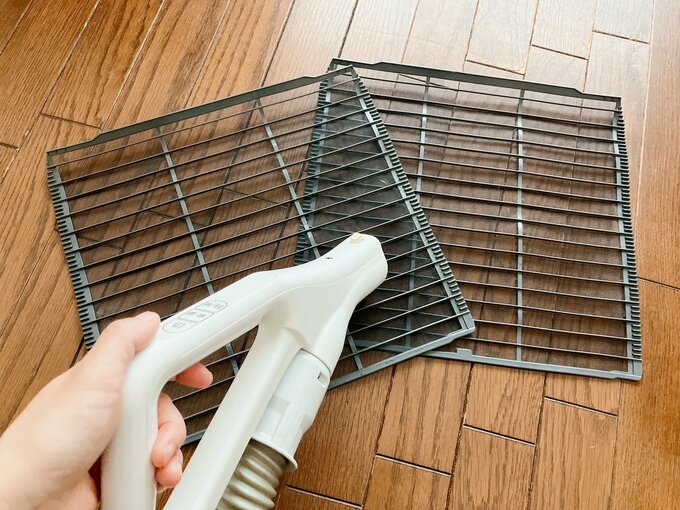 エアコンのフィルターに掃除機をかけている図