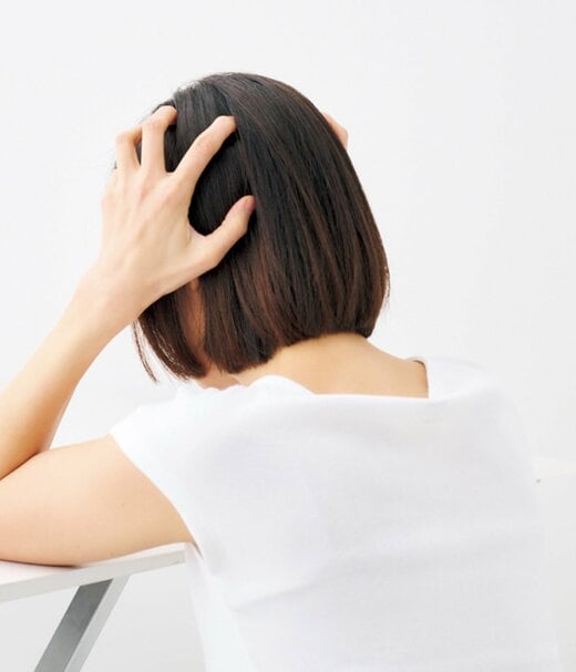 頭頂部下を押し上げる女性