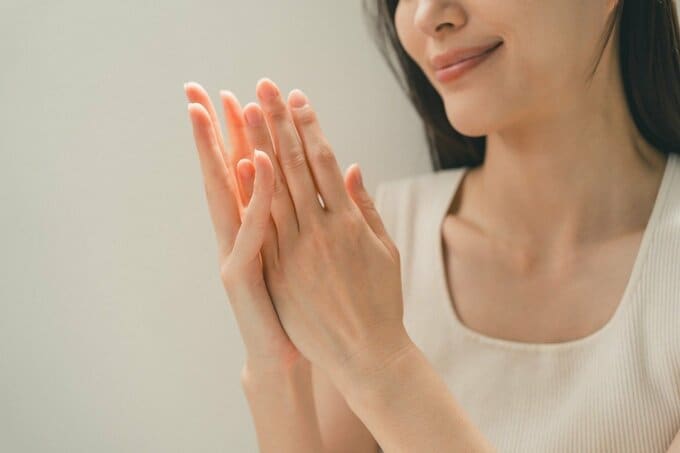 重ね合わせた両手を見る女性のイメージ画像