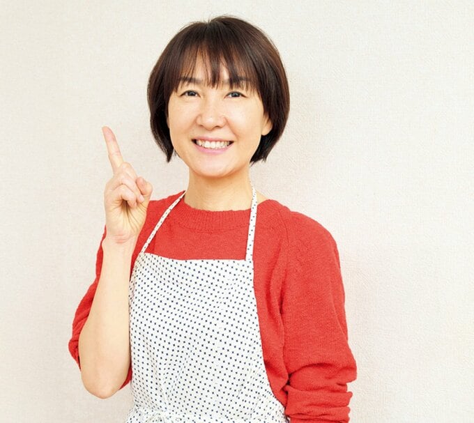 指を立てて微笑むエプロン姿の女性