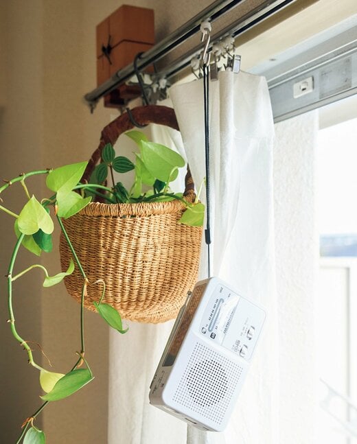 カーテンレールにつり下げられた充電ラジオと観葉植物