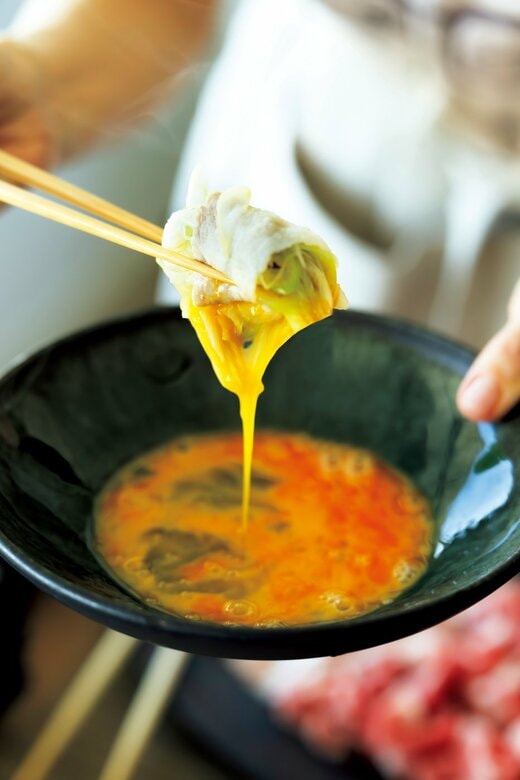 黒い器に入れた生卵に、豚しゃぶを絡めて持ち上げる様子