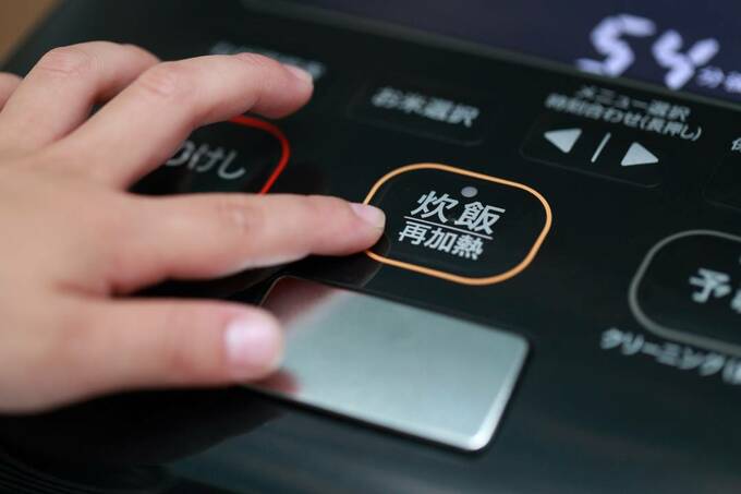 炊飯器の炊飯ボタンを押す