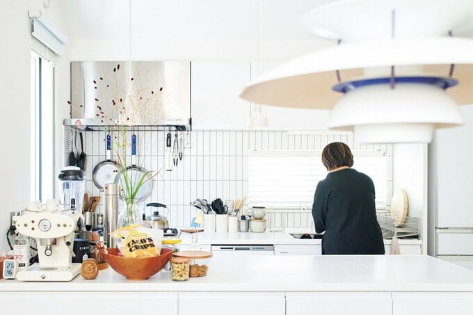 白が基調のキッチンに立つ女性