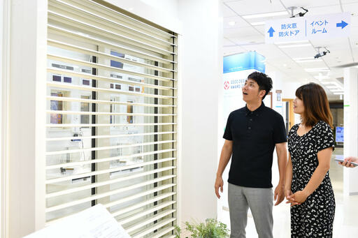 白いブラインドの前で驚く2人