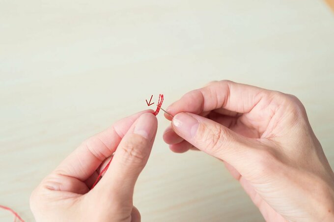 尖らせた糸先に、針から迎えにいくように針穴に通す