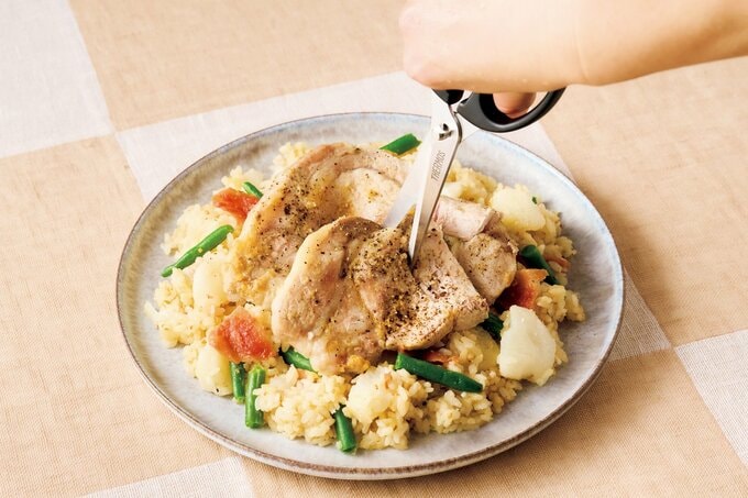 皿に盛られた「長イモと豚肉の梅みそ炊き込みご飯」の豚肉をハサミで切る様子