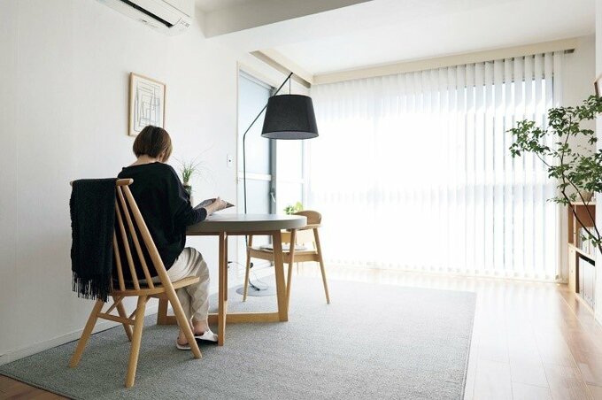 日の光が差し込む明るいダイニングで読書をする女性