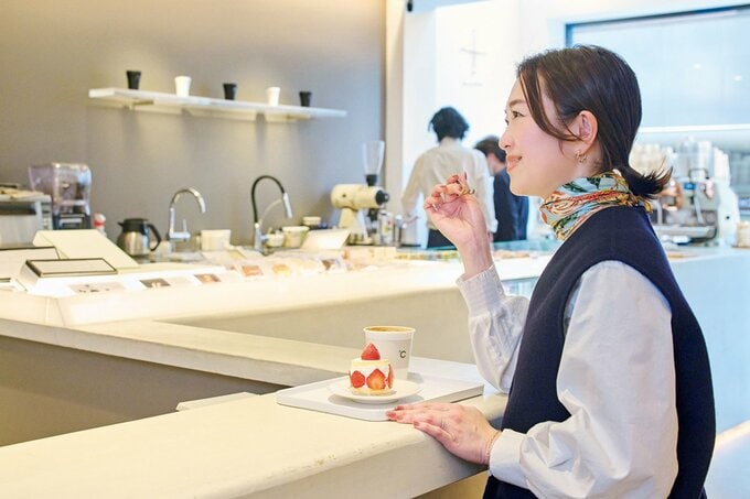 白が基調のカフェカウンターでいちごのケーキを食べる女性